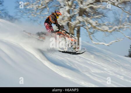 Atleta su una motoslitta spostando in montagna Foto Stock