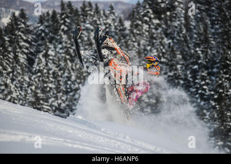 Atleta su una motoslitta spostando in montagna Foto Stock