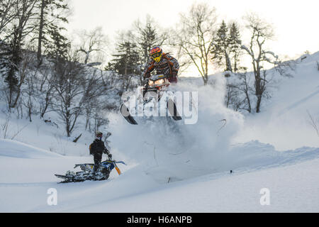 Atleta su una motoslitta spostando in montagna Foto Stock