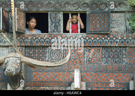 Toraja famiglia pongono per la telecamera nella finestra di Toraja casa tradizionale chiamato Tongkonan Buntu a Pune, Nord Toraja. Foto Stock