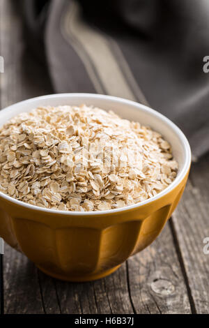 Laminato secco farina di avena nella ciotola sul vecchio tavolo in legno. Foto Stock