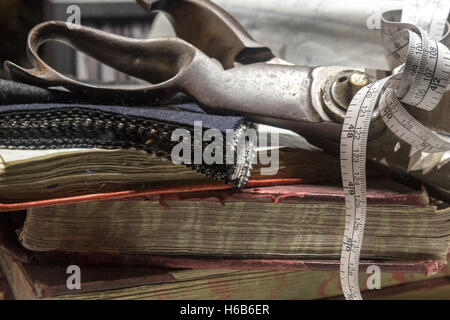 Raccolta di sarti forbici, Suit panno, un nastro di misurazione e Insieme di libri. Foto Stock