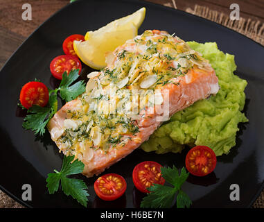 Di salmone al forno con formaggio e crosta di mandorle e guarnita con purè di patate e piselli verdi Foto Stock