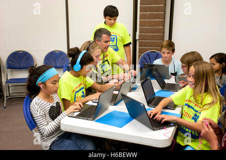 Un insegnante di scuola elementare aiuta i suoi studenti con una classe di animazione digitale il progetto in Mission Viejo, CA. Nota colorato progetto T Shirts. Foto Stock