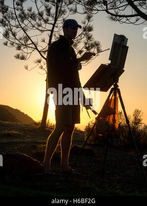 Pittura al suo cavalletto, un artista che si stagliano contro un tramonto sulla cima di una collina nella Laguna Niguel, CA. Foto Stock