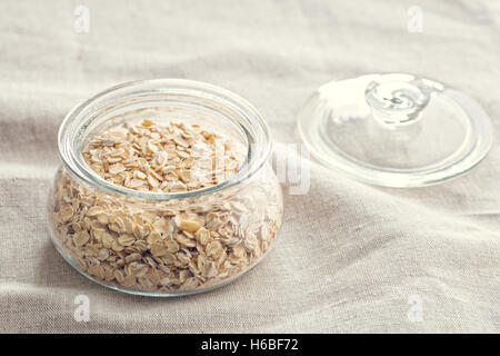 A secco di fiocchi d'avena e laminati in barattolo sulla tovaglia. Foto Stock