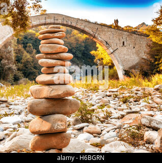 Cumulo di pietre nella parte anteriore di 500 anni gobbo Rinascimento ponte di collegamento tra due rive con singolo span in campagna italiana Foto Stock