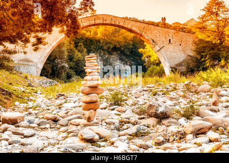 Cumulo di pietre nella parte anteriore di 500 anni gobbo Rinascimento ponte di collegamento tra due rive con singolo span in campagna italiana Foto Stock