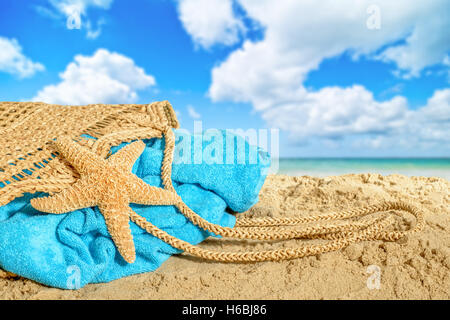 Borsa da spiaggia sdraiato sulla sabbia con asciugamano e stelle marine Foto Stock