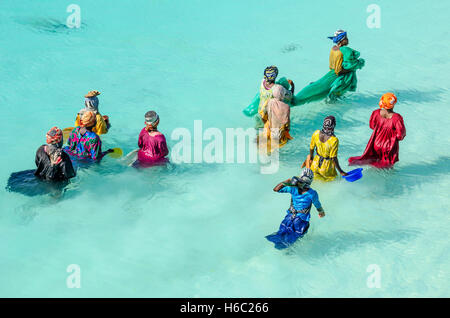 Le donne con abiti colorati la pesca in acqua poco profonda. Essi stanno portando i loro vasi, con la quale si caccia piccoli pesci Foto Stock