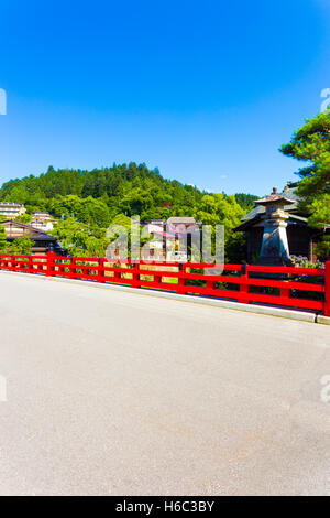 Una foresta di montagna e cielo blu dietro il red Naka Bashi bridge all'entrata della storica città vecchia di alipine città di Takayama Foto Stock