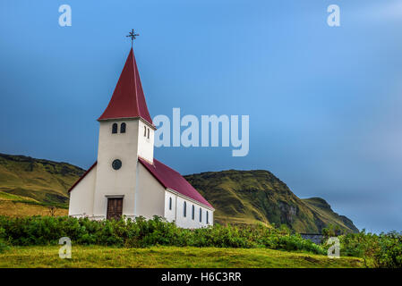 Nuvole pesanti al di sopra della chiesa luterana in cima a una montagna nella città di Vik in Islanda. Lunga esposizione. Foto Stock