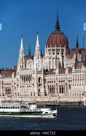 Un turista in barca a vela passato il Parlamento ungherese edificio in Budapest, Ungheria. Foto Stock