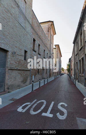 Vecchia strada stretta con grande cartello Stop sull'asfalto a Rimini, Italia. Foto Stock