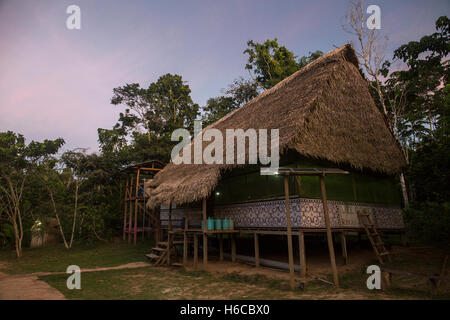 Un ayahuasca medicina centro di guarigione e maloca nell'Amazzonia peruviana foresta pluviale in una radura della giungla al tramonto vicino a Iquitos Foto Stock