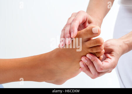 Extreme close up terapista facendo riflessologia plantare su umano del piede femminile. Isolato su sfondo bianco. Foto Stock