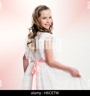 Close up ritratto in studio della cute girl in comunione vestito. Foto Stock