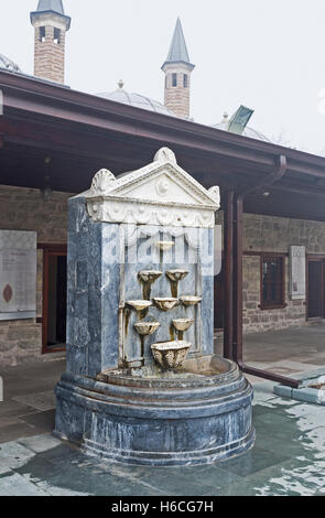 La piccola fontana di pietra nel cortile del museo di Mevlana, Konya, Turchia. Foto Stock