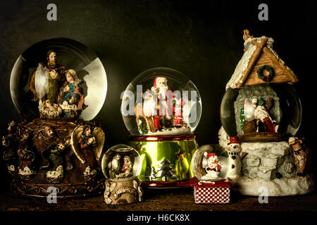 Natale carta vintage, fiocchi di neve globi di cristallo con statuette di natale su sfondo rustico Foto Stock