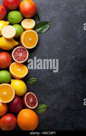 Fresche e mature agrumi. I Limoni e limette e le arance in pietra scura sullo sfondo. Vista da sopra con lo spazio di copia Foto Stock