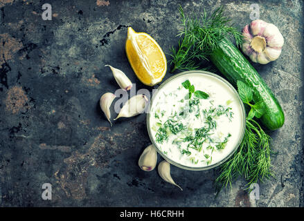 Salsa Tzatziki con ingredienti cetrioli, aglio, aneto, limone, menta. Sfondo di cibo. In stile vintage tonica foto Foto Stock