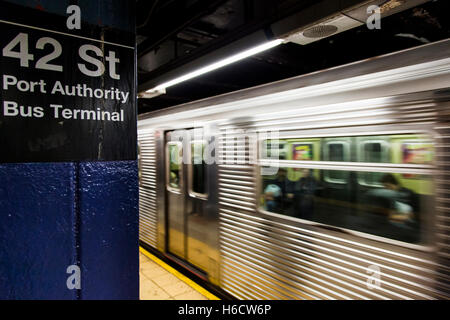 Treno della metropolitana swifting dietro il segno raffigurante è il 42nd St. Station a Manhattan, New York. Foto Stock