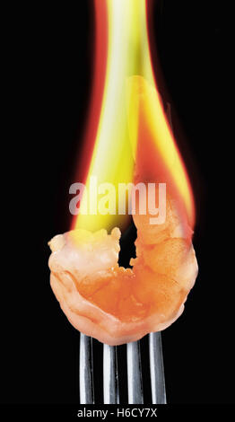Flaming gamberi su una forcella d'argento. Foto Stock