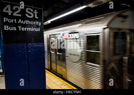 Treno della metropolitana swifting dietro il segno raffigurante è il 42nd St. Station a Manhattan, New York. Foto Stock