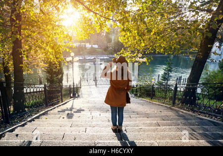 Donna con cappello vicino al lago con Giallo autunno gli alberi del parco Foto Stock