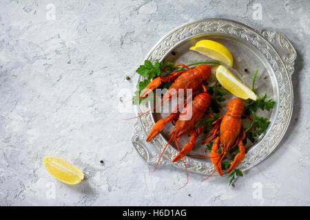 Aragosta bollita, limone e prezzemolo su un sfondo di calcestruzzo. Sfondo di cibo. Il concetto di mangiare sano. Vista superiore, copia spac Foto Stock