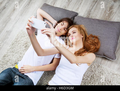 Bella coppia Giovane rilassante sul pavimento a casa e prendendo un selfie Foto Stock
