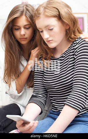 Ragazza con un amico di essere vittima di bullismo mediante messaggio di testo Foto Stock