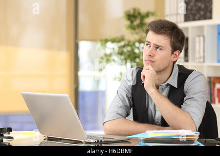 Serio dubbio imprenditore pensando e guardando dal lato seduta a una scrivania in ufficio Foto Stock