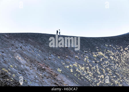 La gente che camminava sul bordo di un cratere sul Monte Etna e Catania, Sicilia, Italia Foto Stock