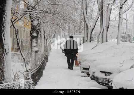 Bucarest, Romania, 17 Gennaio 2016: Un uomo cammina sulla strada durante una nevicata a Bucarest. Foto Stock