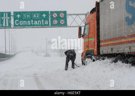 Autostrada A2, Romania, 17 Gennaio 2016: un camionista pale neve per liberare il suo camion sulla chiusa autostrada A2, la principale commercia Foto Stock
