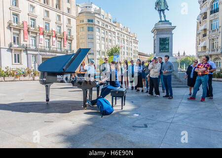 Una femmina di pianista suona il pianoforte di fronte a molti guardato durante Madrid piena di pianoforti a Madrid, Spagna. Foto Stock