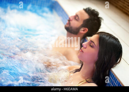 Close up ritratto della coppia giovane relax nel centro termale con jacuzzi. Coppia insieme nella bolla di acqua con gli occhi chiusi. Foto Stock