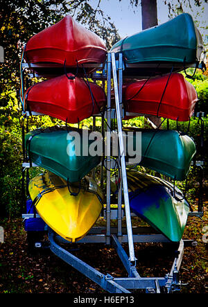 Canoe colorati disposti in rack memorizzati su una macchina parcheggiata rimorchio Foto Stock