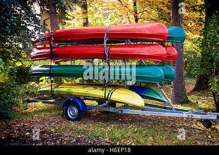 Canoe colorati disposti in rack memorizzati su una macchina parcheggiata rimorchio Foto Stock