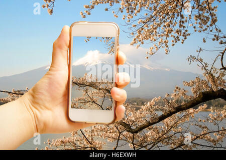 Mano azienda smart phone (Telefono cellulare) con il Monte Fuji vista dal lago Foto Stock