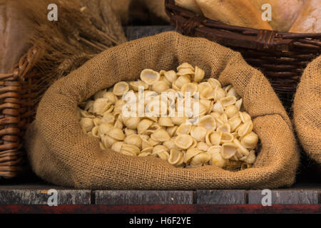 Non cotti Pasta italiana nel sacco di iuta sul tavolo di legno Foto Stock