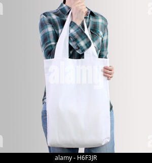 La ragazza è in possesso di bianco in cotone bianco tote bag, design mockup. Fatte a mano borsa shopping per le ragazze. Foto Stock