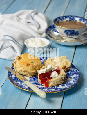 Scones con marmellata e crema fresca sulla piastra vintage con tazza di tè in background Foto Stock