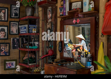 La riflessione di un venditore di frutta sullo specchio di un barbiere in una strada di Hanoi. Foto Stock