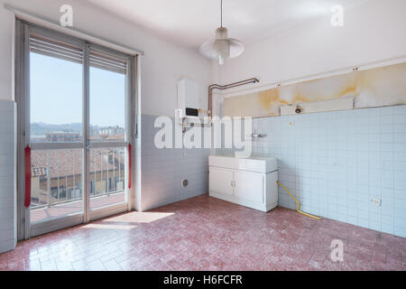 Vecchia cucina vuota stanza con pavimento piastrellato e pareti Foto Stock