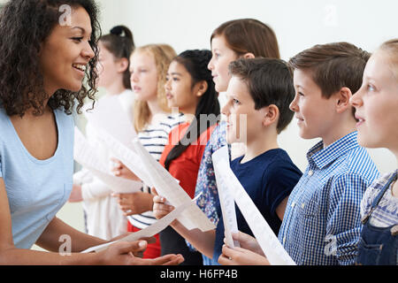 I bambini in coro scolastico essendo incoraggiati dall'insegnante Foto Stock