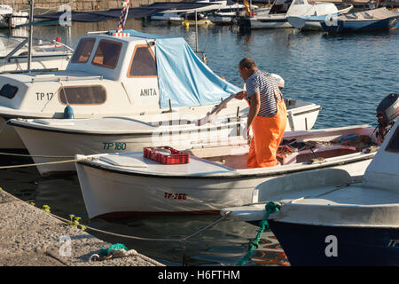 Un pescatore scarica il pesce su una piccola barca da pesca nel porto di Trpanj Croazia Foto Stock