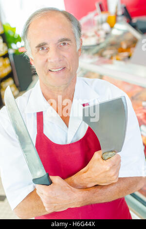 Butcher tenendo il coltello e geniale, braccia incrociate Foto Stock