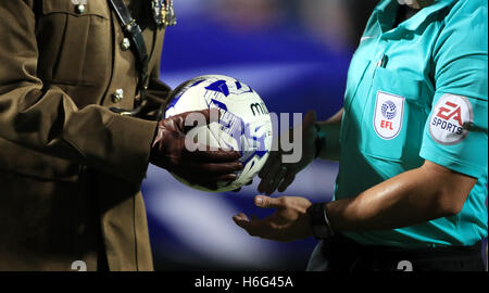 Un membro delle forze armate mani il match ball di arbitro James Adcock prima di iniziare la partita il match durante il cielo di scommessa match del campionato a Loftus Road, Londra. Foto Stock